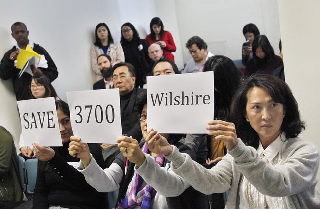 Jamison Services, the biggest real estate firm owned by a Korean-American, is drawing heavy criticism from Koreatown residents after proposing to build a skyscraper as a replacement of the neighborhood’s only green land. Local residents who attended the public hearing is holding up signs to voice their opposition to the project on Dec. 7. Sang Jin Kim 